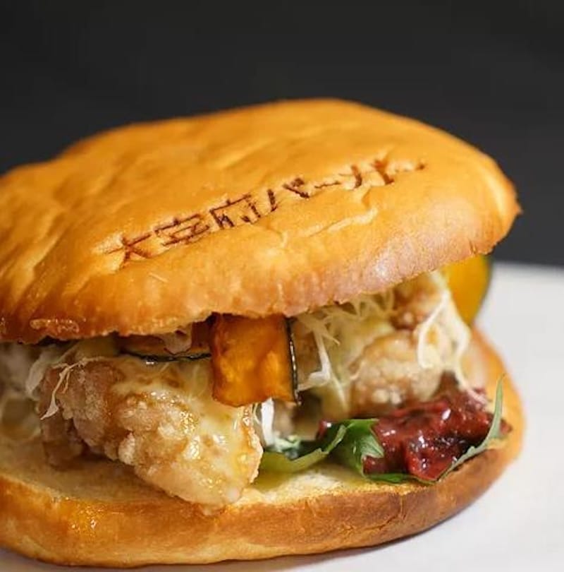 Close-up of a Dazaifu burger with fried chicken and local ingredients