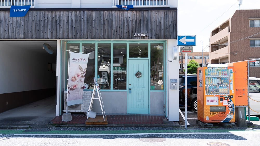 Cute boutique shop facade with a mint green door and brick accents in Fukuoka