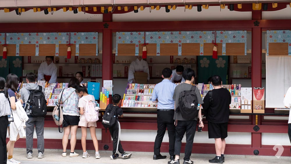 Visitors browsing charms and omamori at the Dazaifu Tenmangu Shrine amulet pavilion